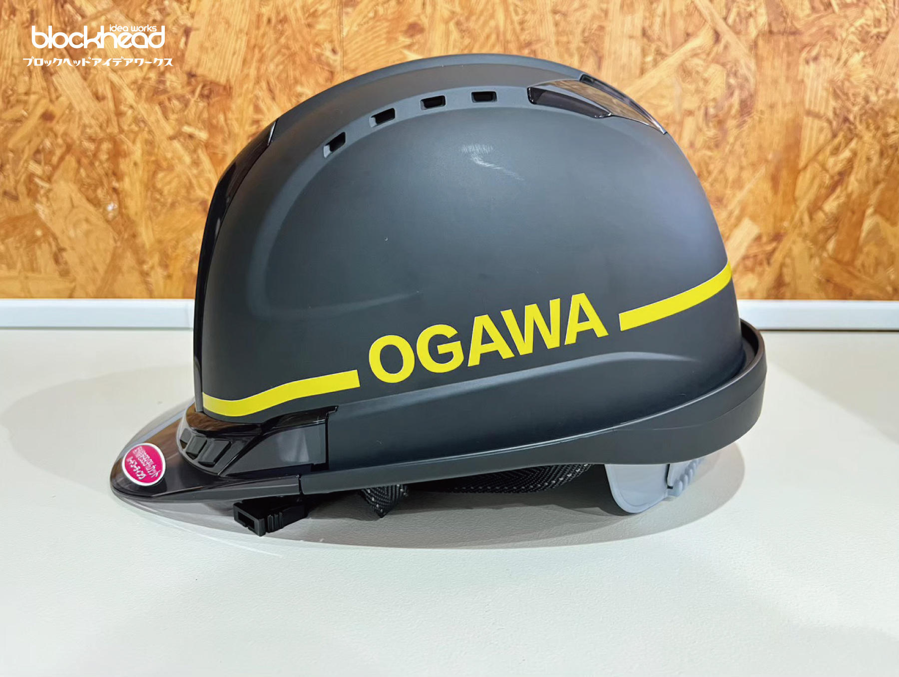 黒に黄色のデザインをしたヘルメット,側面,OGAWAの文字