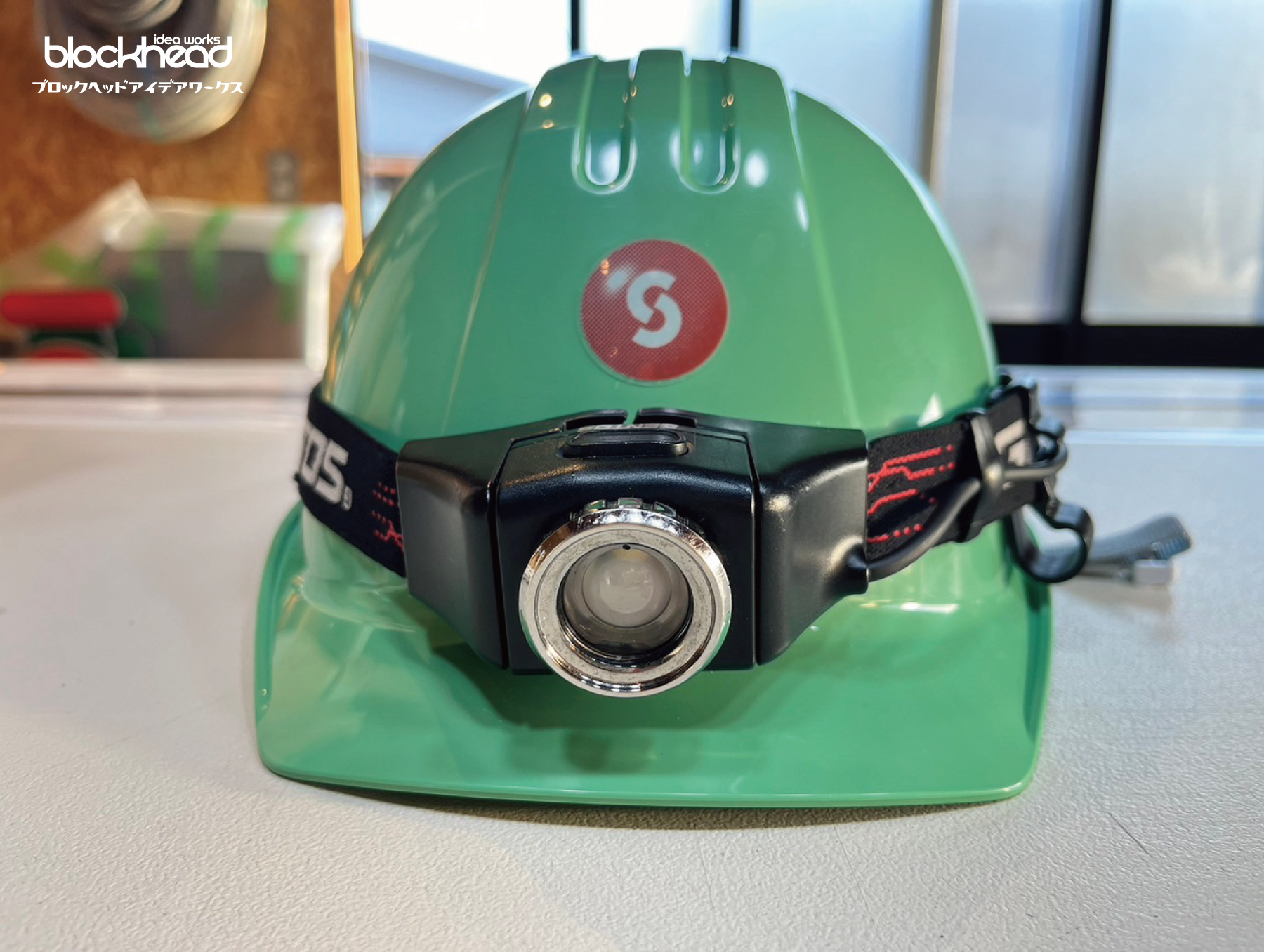 ミントグリーンのヘルメット正面,赤い丸のロゴ